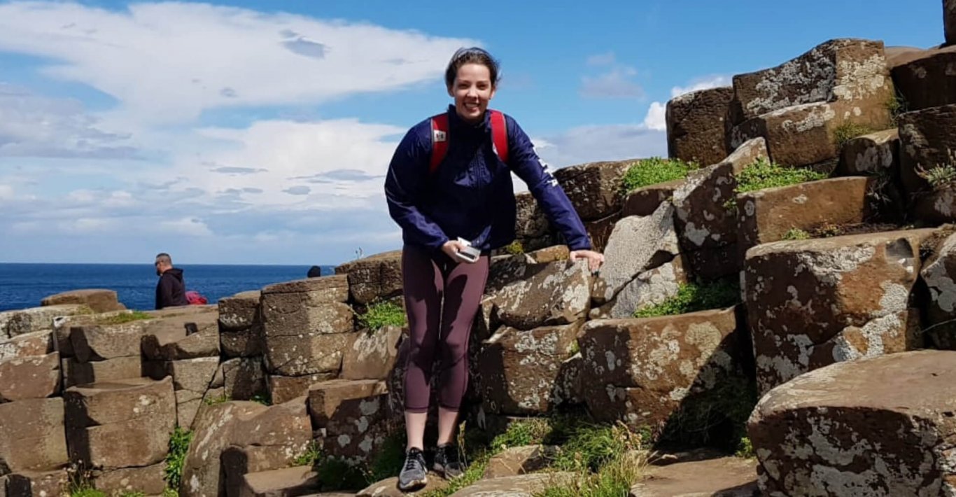 Female guest smiling at the camera while posing on the Giant's Causeway in Northern Ireland