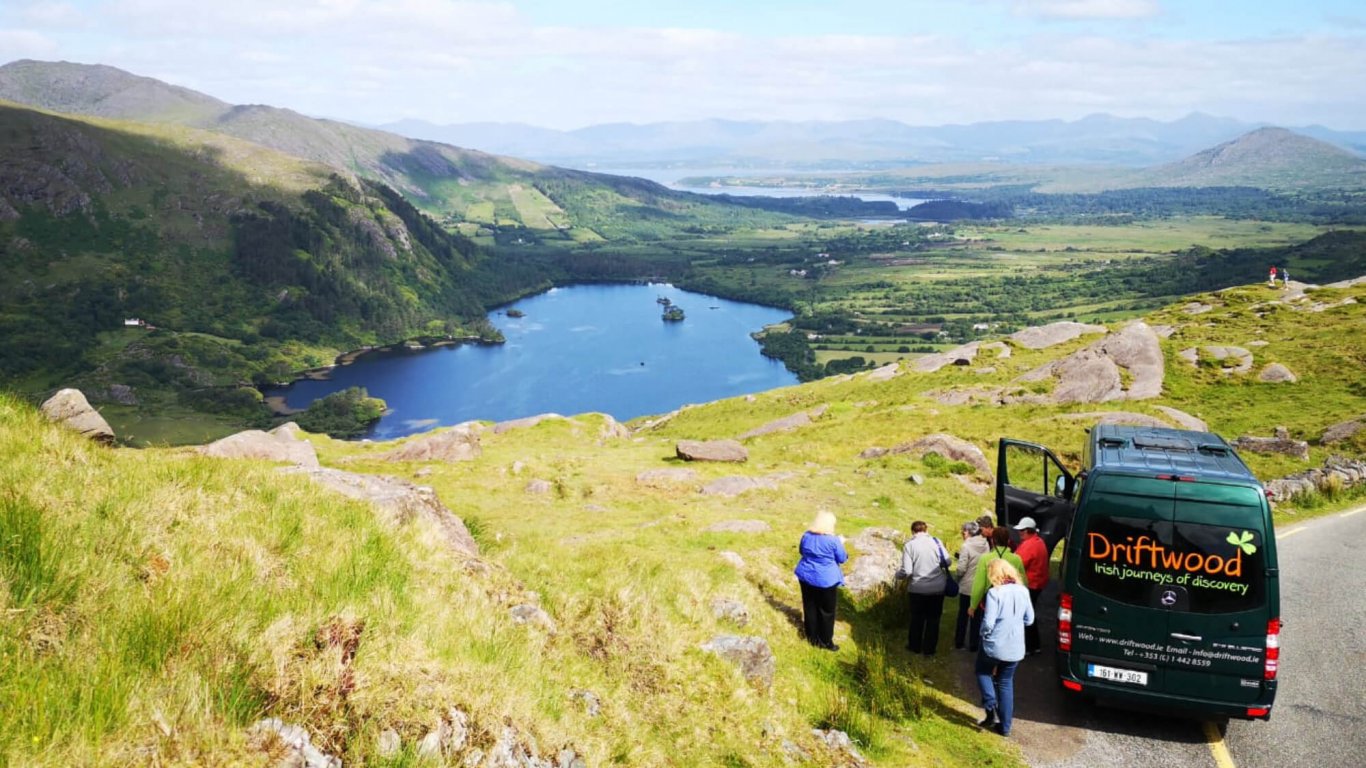 A Driftwood tour vehicle and tour group stopped at a scenic spot on the Healy Pass in Ireland