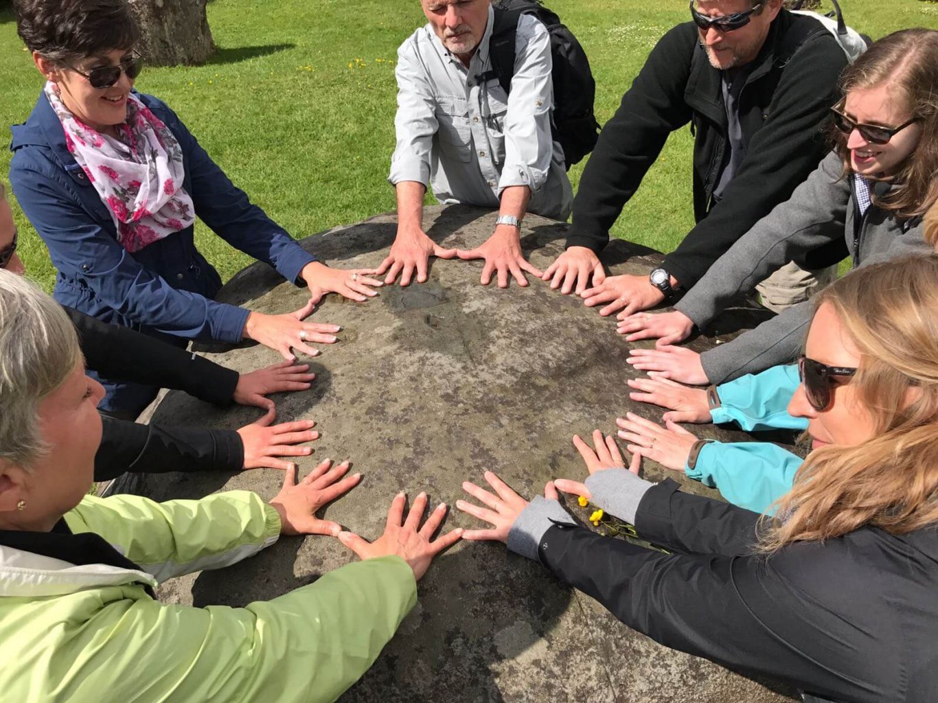 Driftwood tour group place their hands on an ancient stone