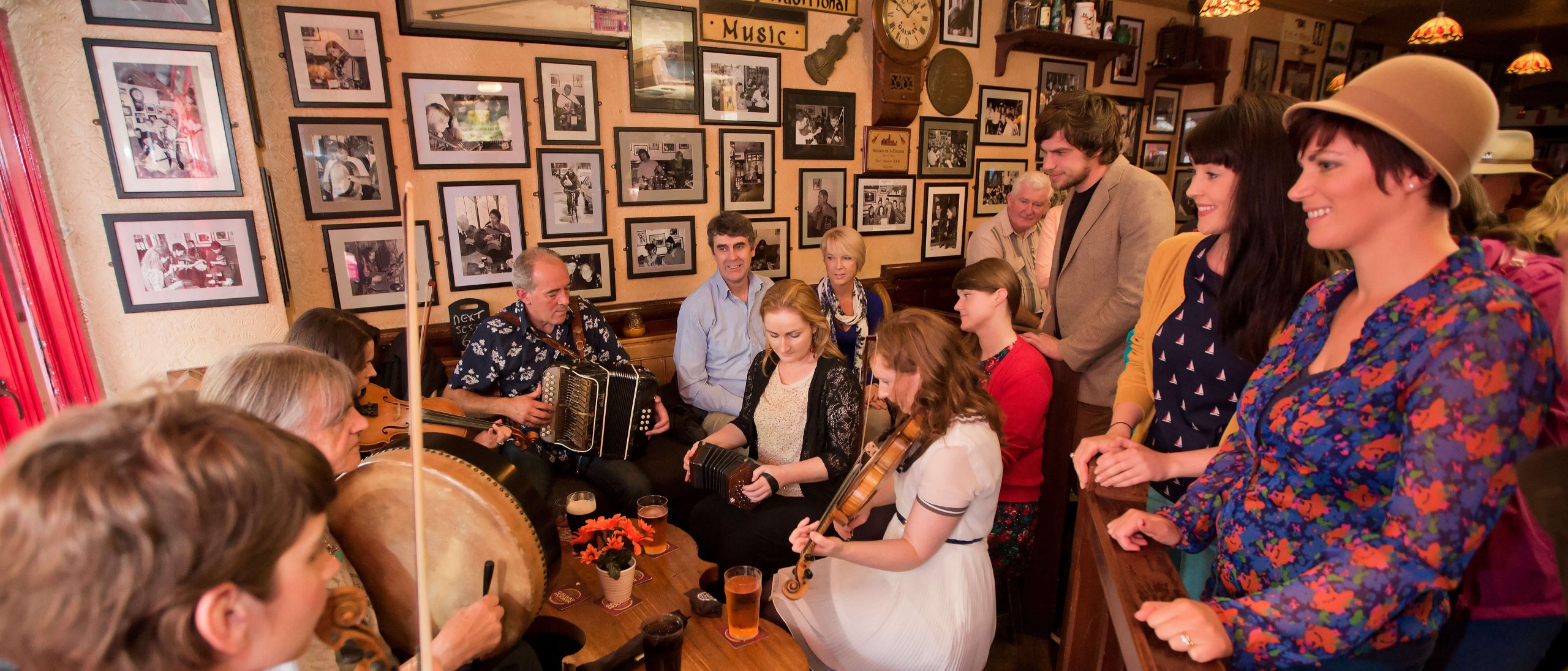 A group of musicians perform traditional Irish music while tourist look on