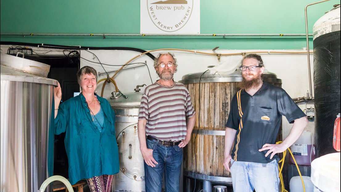 Three brewers stand facing the camera in West Kerry Brewery, Ireland