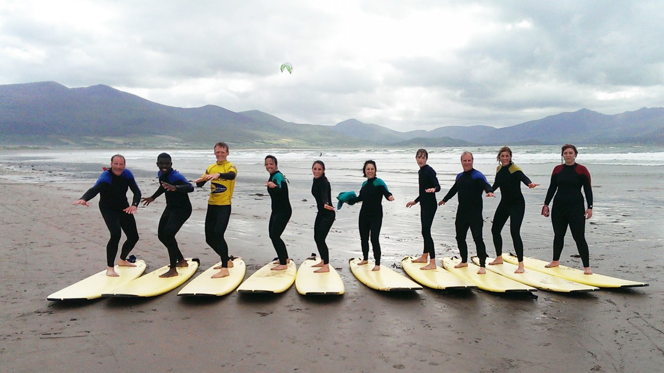 A Vagabond tour group standing on surfboards in Kerry, Ireland