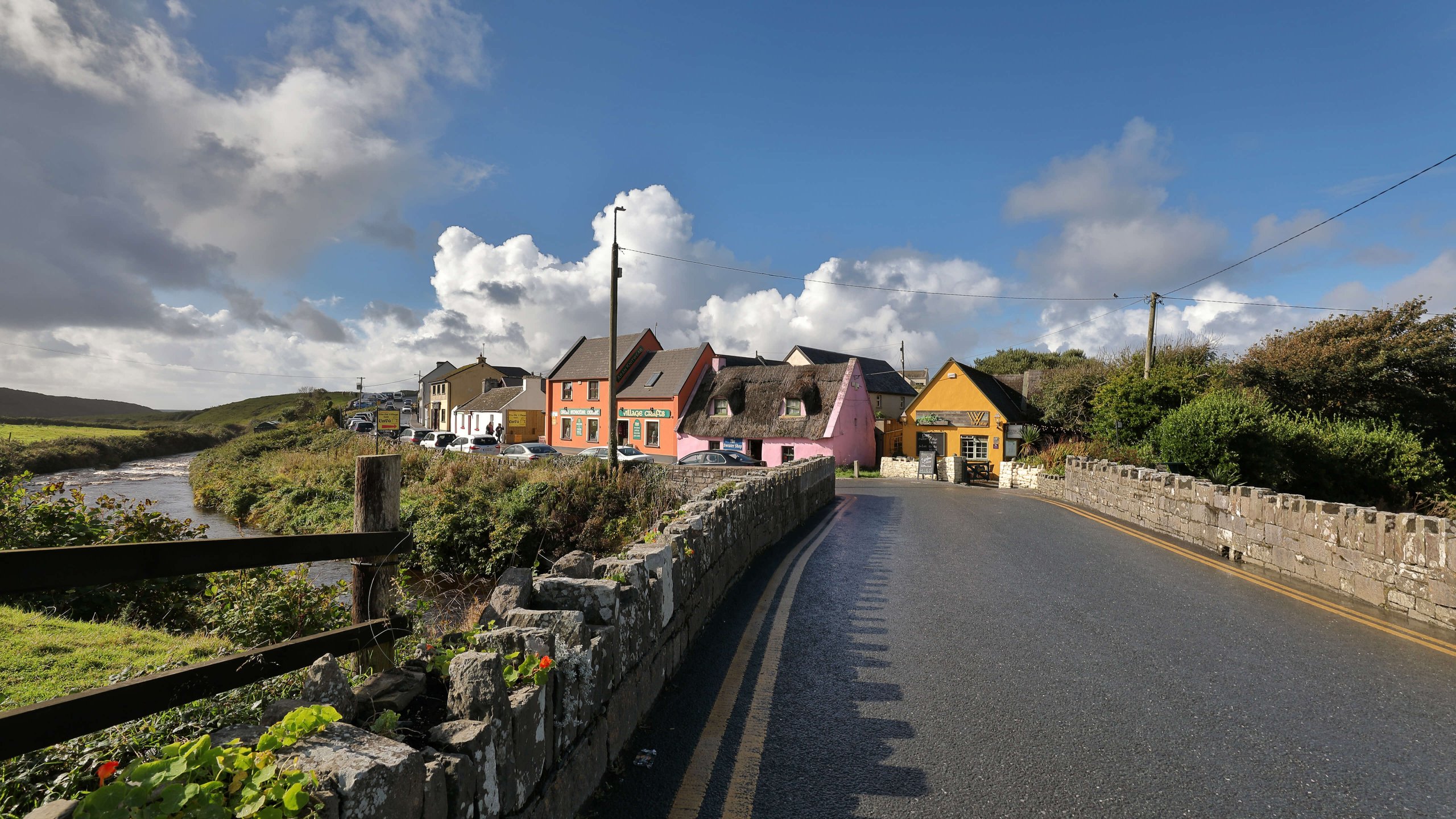 Blue sky and clouds over colourful houses and a bridge in Doolin, Ireland