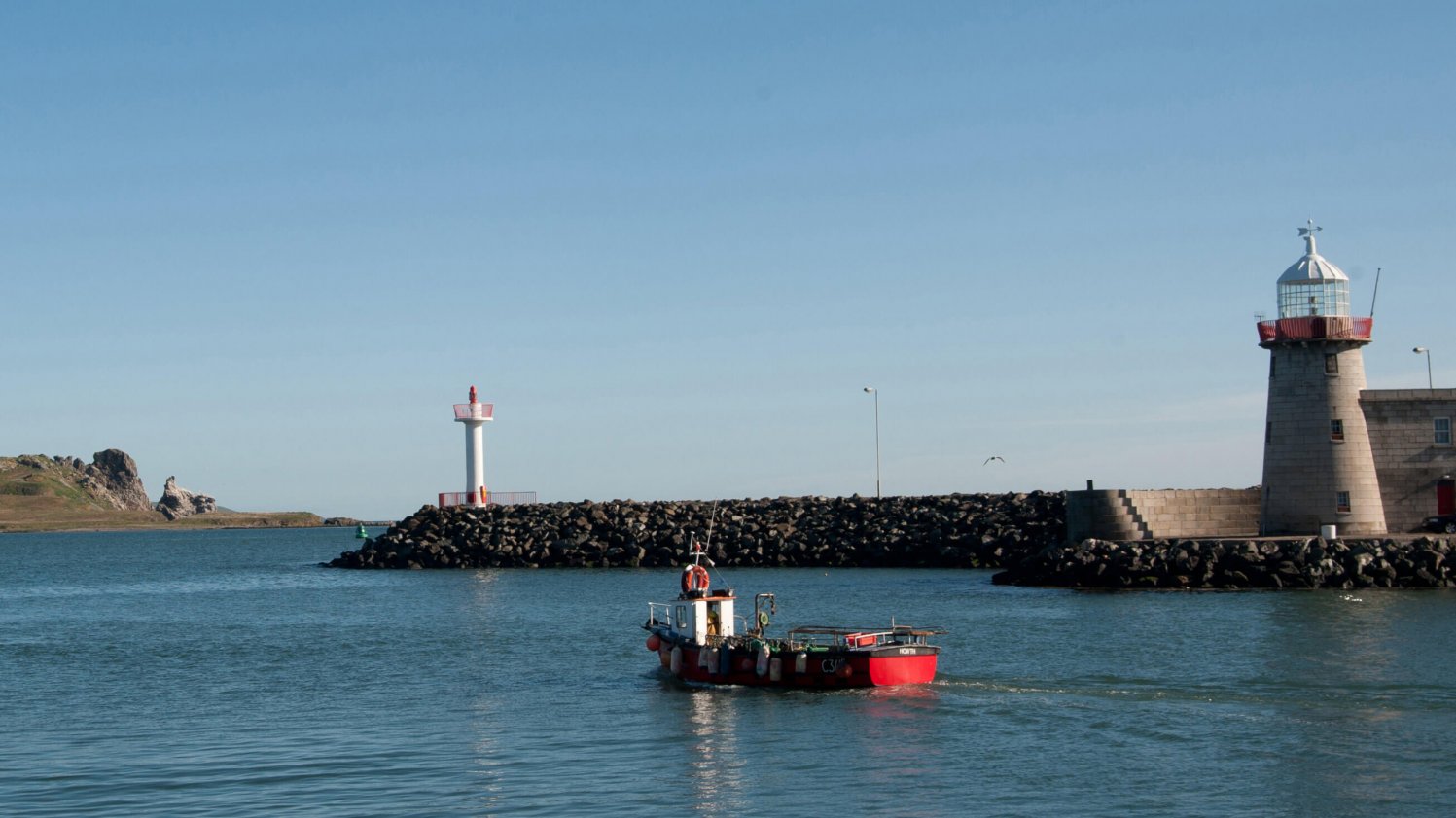 Boat and lighthouse in Howth harbour with Ireland's Eye in the background