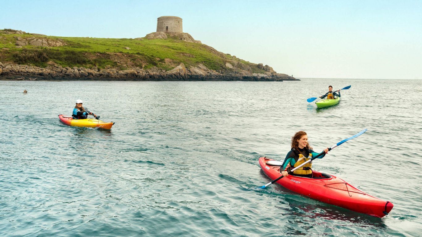 Three young people kayaking int the sea around Dalkey Island 