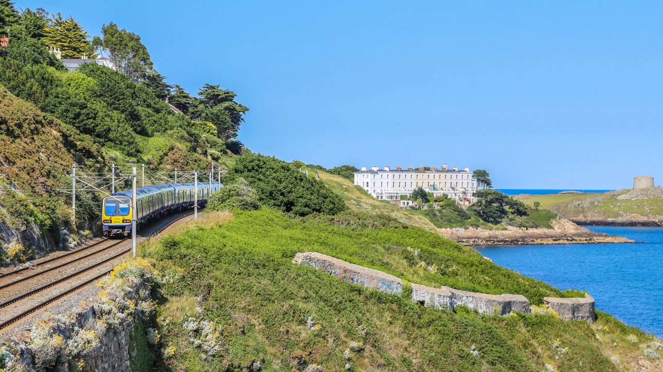 The DART passing through Killiney in the sunshine with a view of Dalkey Island in the distance 