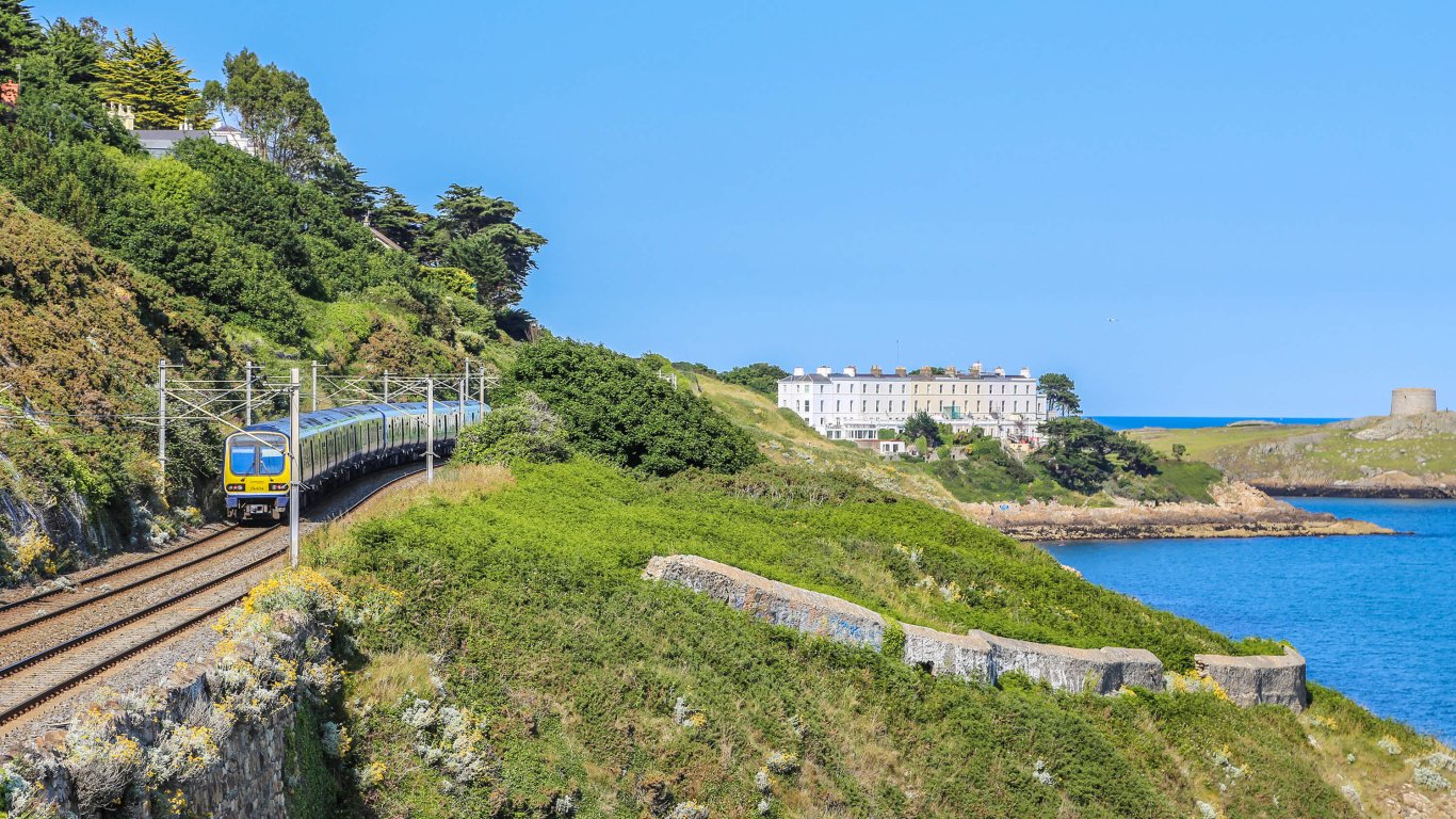 The DART passing through Killiney in the sunshine with a view of Dalkey Island in the distance 