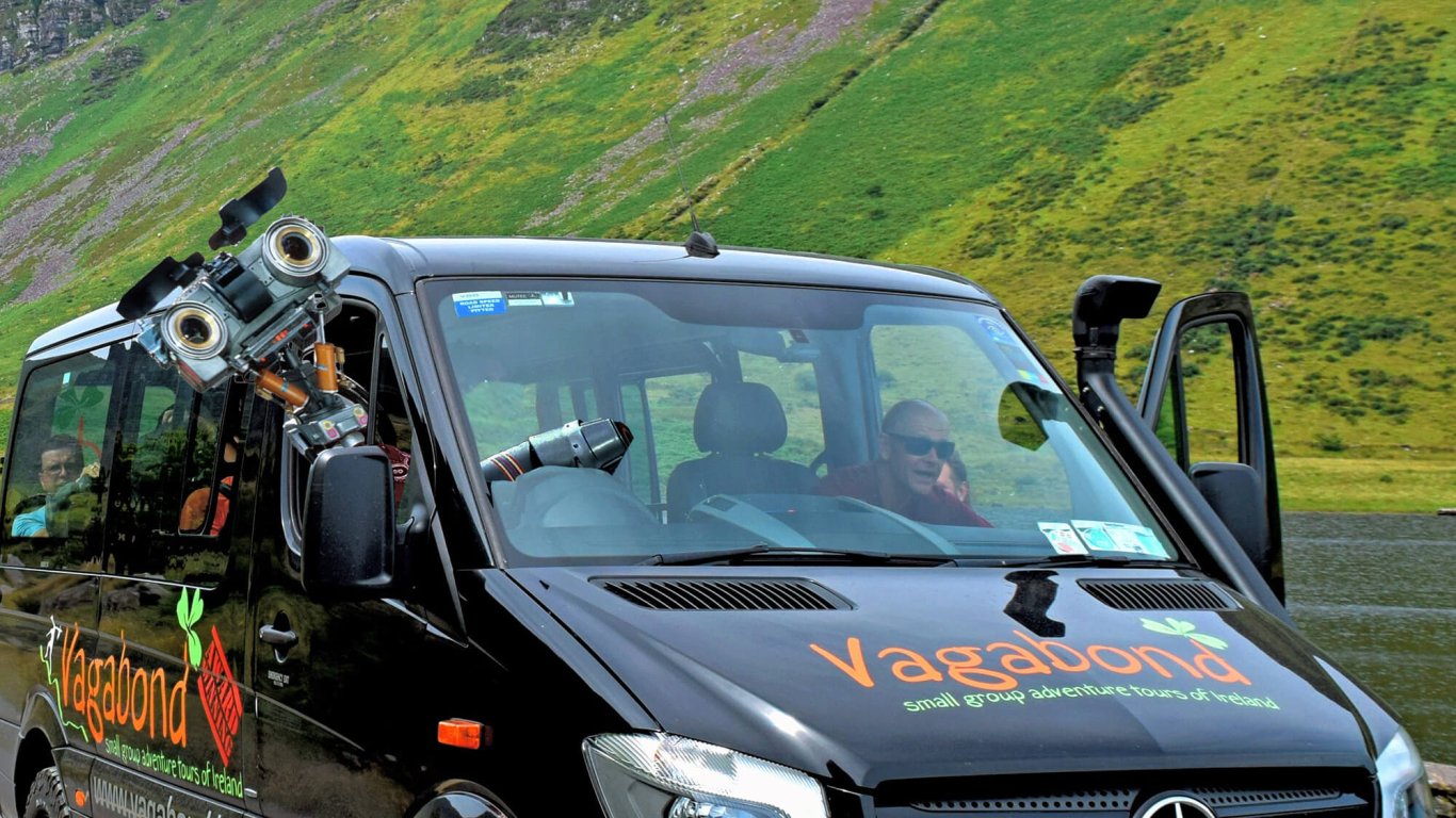 Robot leaning out of a van window with green landscape in background