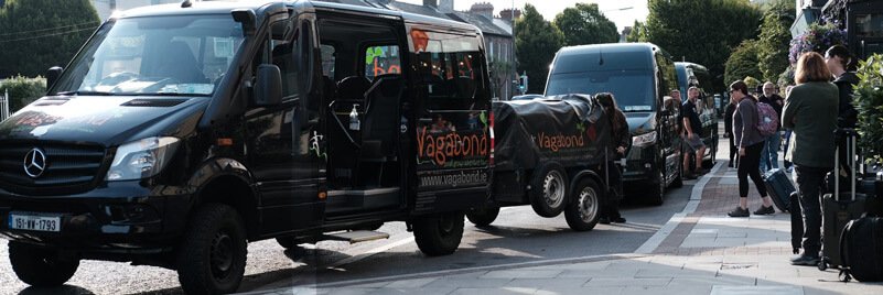 Tour guests waiting to board a row of minibus tour vehicles in Dublin, Ireland