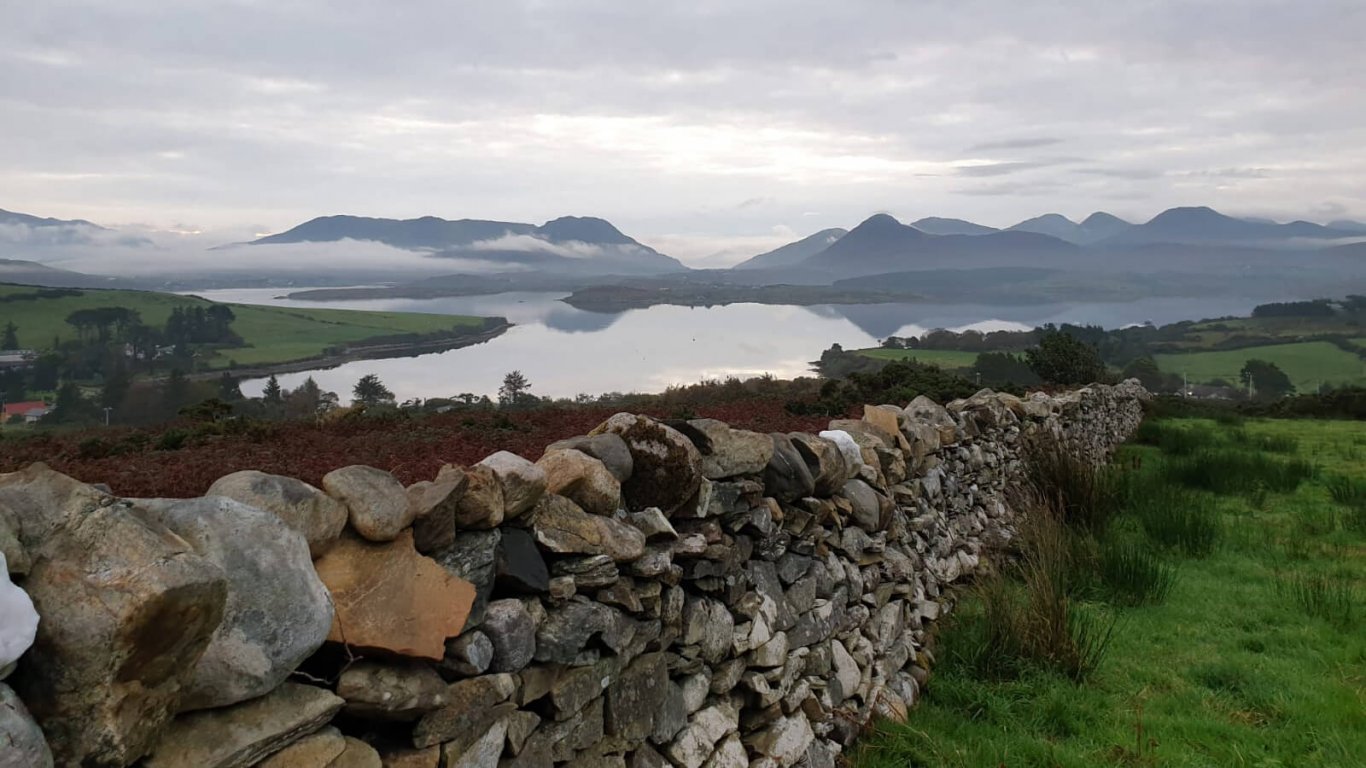 Twelve Bens mountain range with dry stone wall and field in Ireland