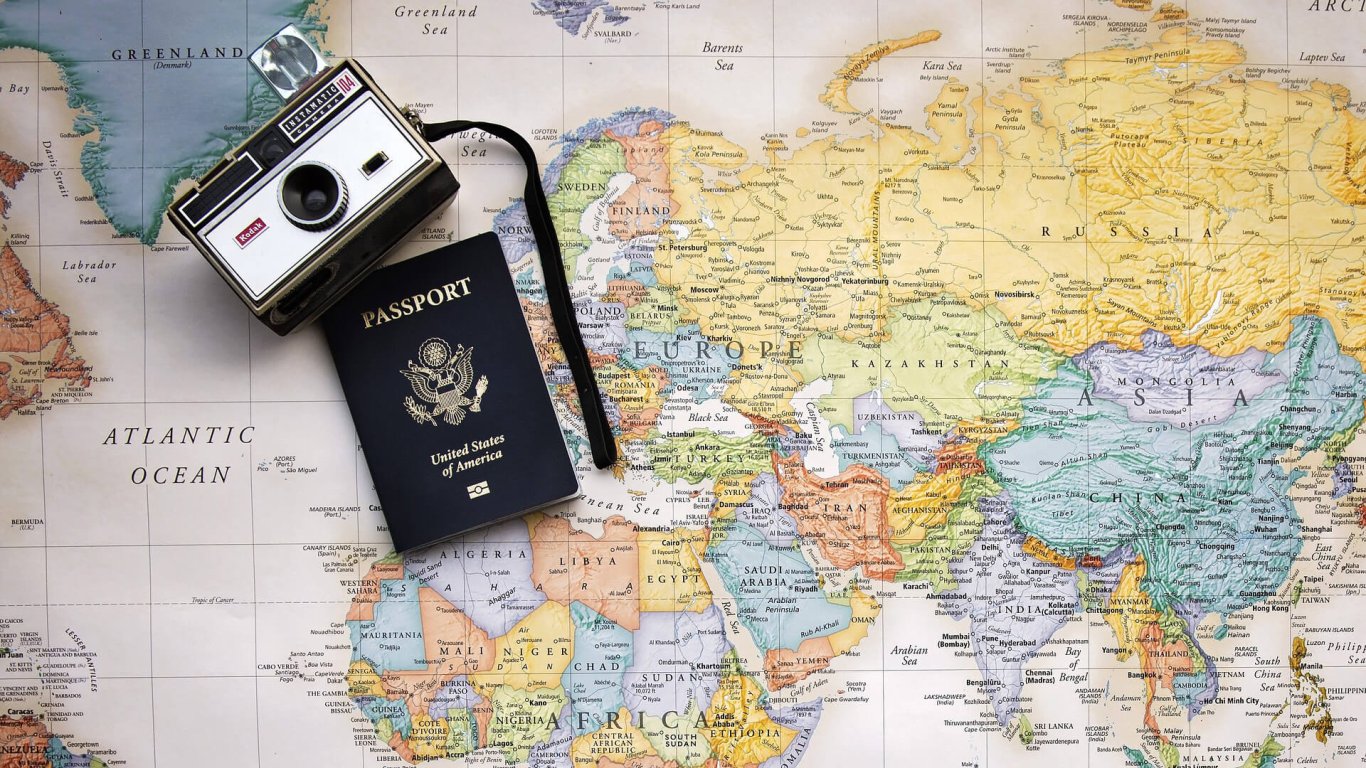 US Passport and retro camera on top of a map of the world