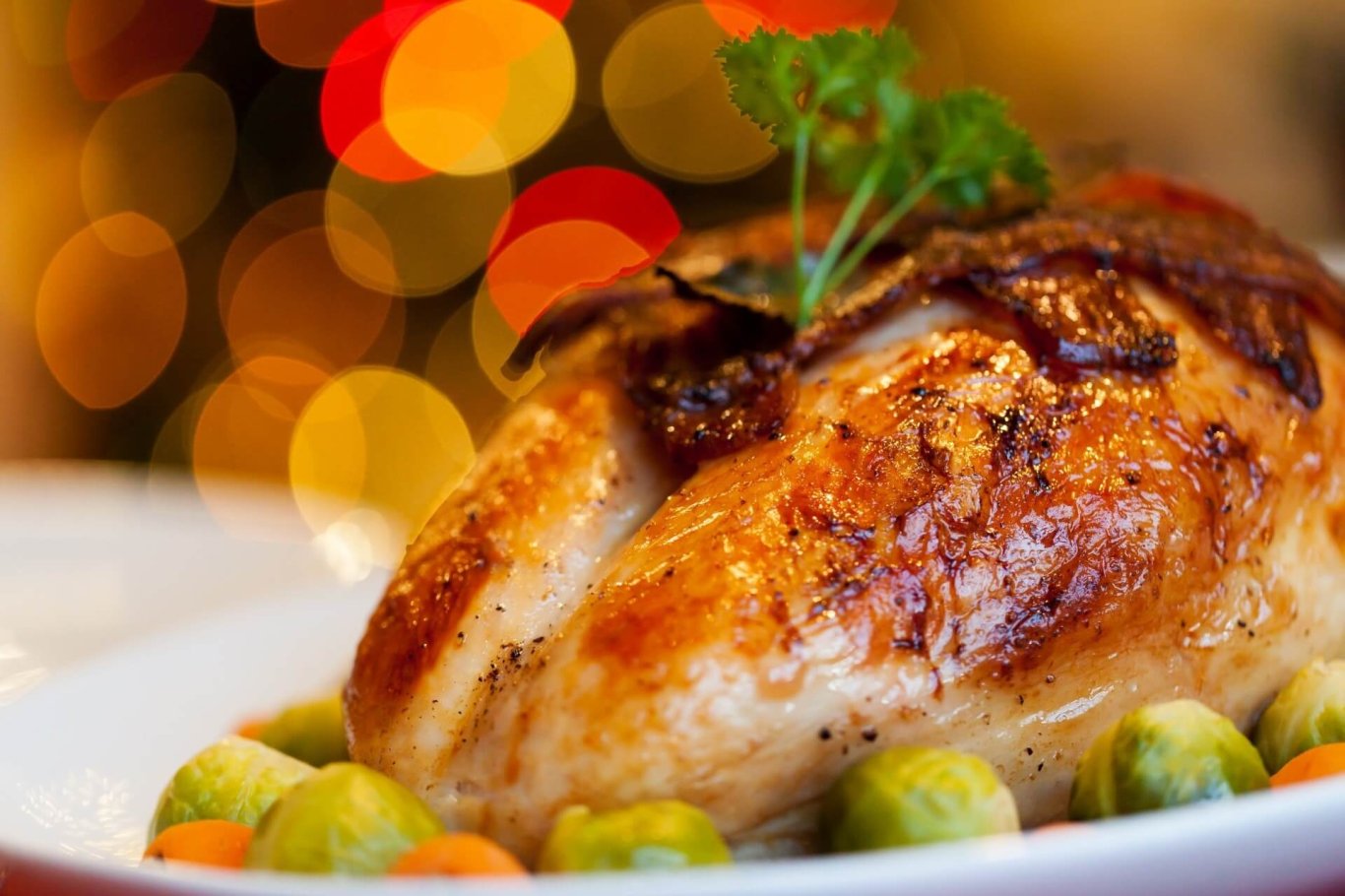 A close up of a Christmas Turkey surrounded by carrots and brussel sprouts