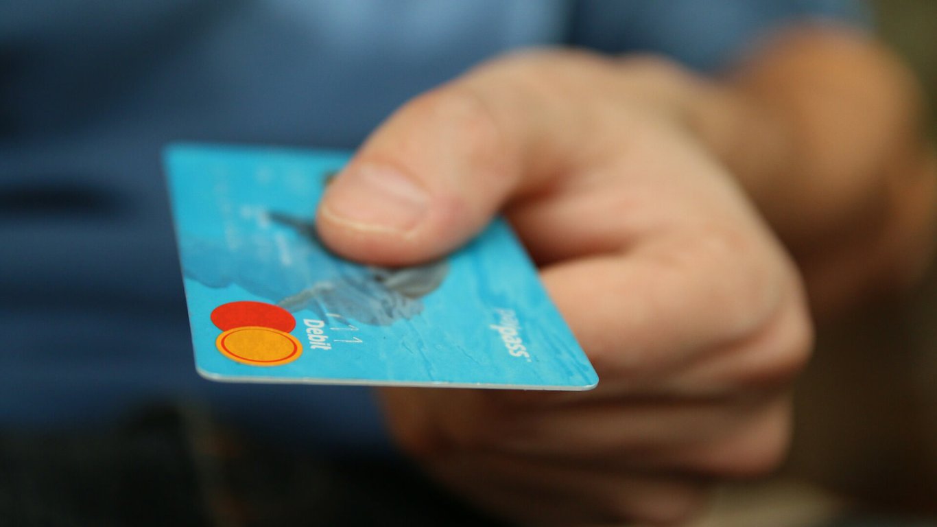 A man's hand holding out a credit card 