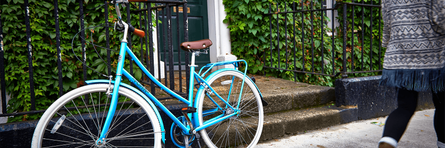 A blue bike parked in front of a Georgian house covered in ivy