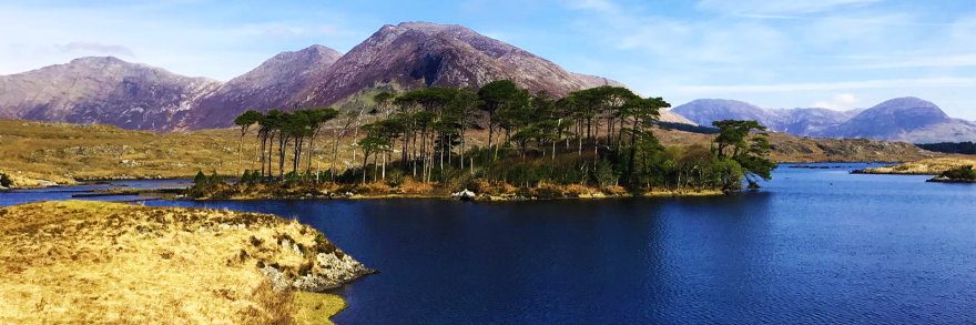 An aerial view of Derrynane lake which is surrounded by beautiful landscape and mountains in the distance 