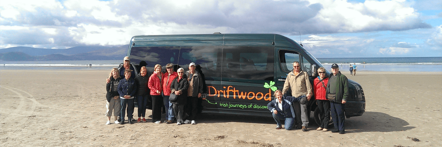 A Driftwood group standing in front of their tour bus on a beach