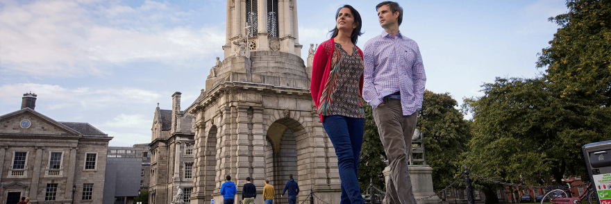 A couple walking through trinity college on a sunny day