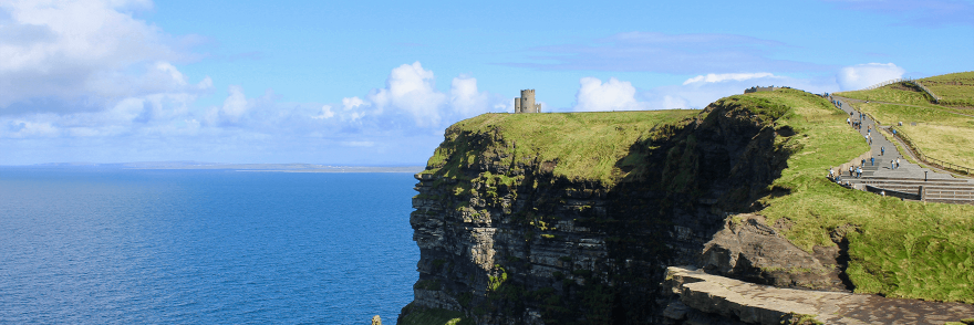A view of the Cliffs of Moher on a sunny day with blue skies overlooking the sea