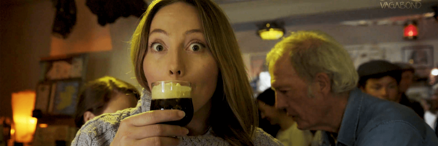 A woman drinking an Irish coffee in a crowded pub 