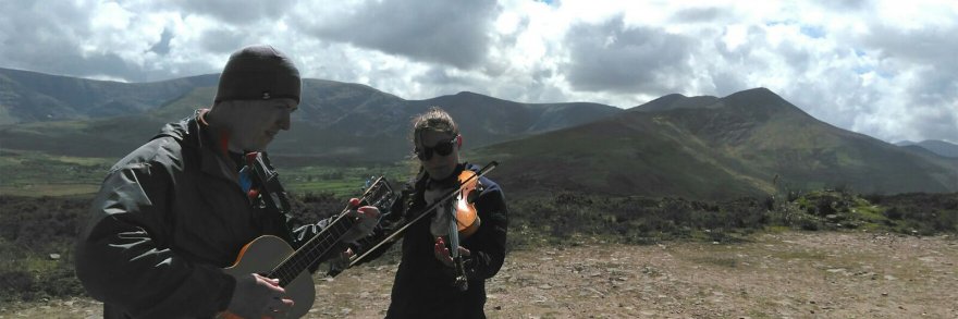Two guests on a mountain playing the guitar and violin
