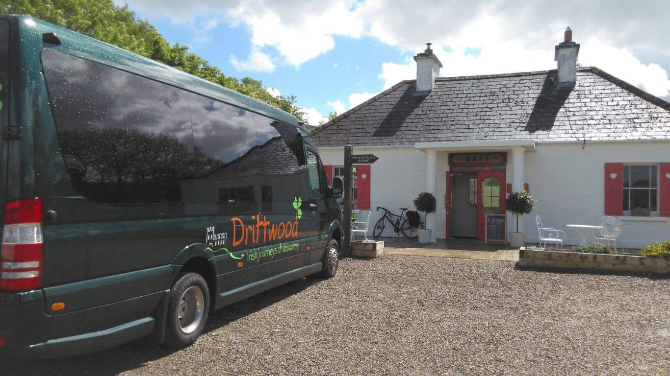 A Driftwood mini-coach parked outside a traditional Irish cottage 