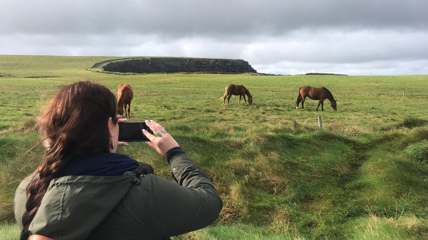    Two horseback riders on a beach beside Ben Bulben in Ireland