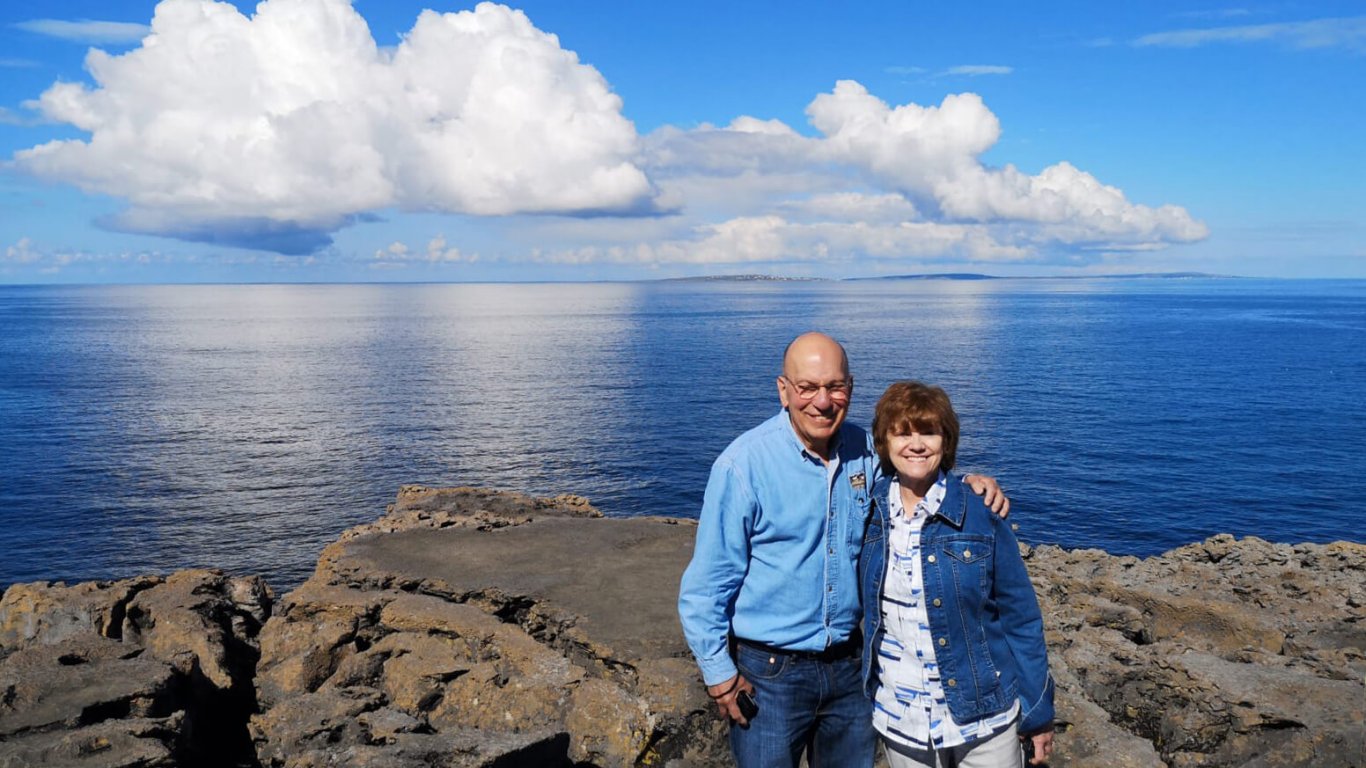Two tour guests in front of a blue sky and ocean in Ireland