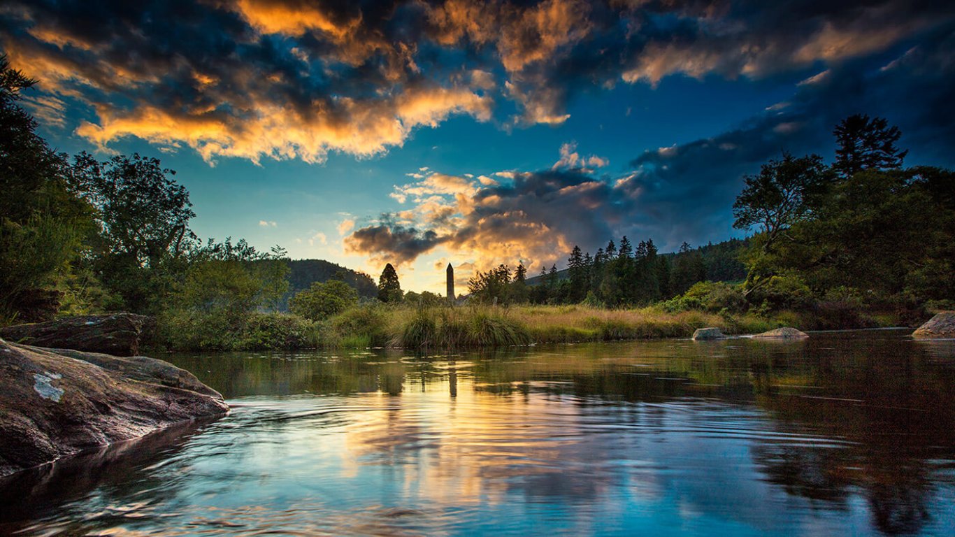 River running through Glendalough with the round tower in the distance at dusk