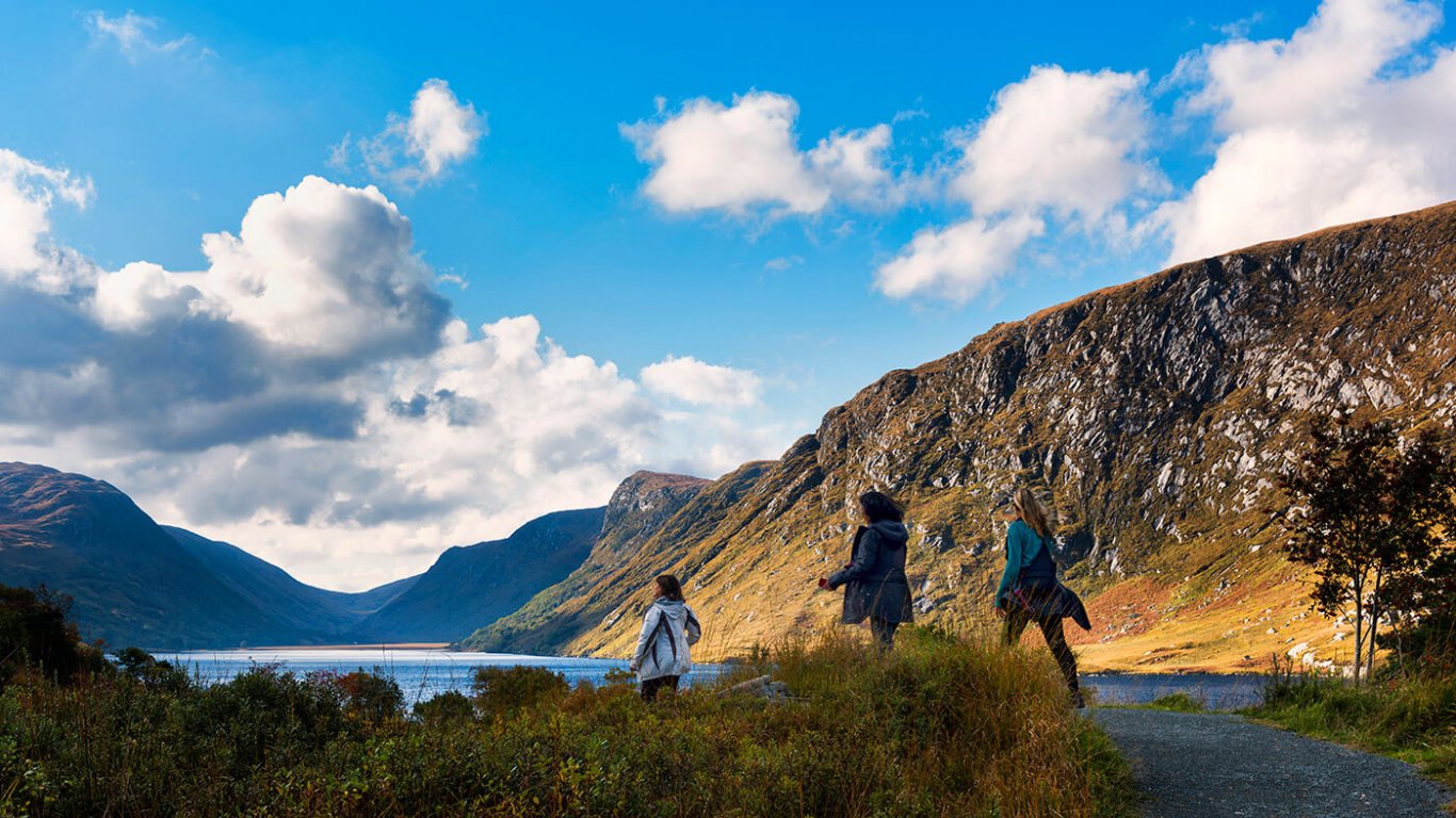 Guests hiking in Glenveagh National Park surrounded by mountains and a lake