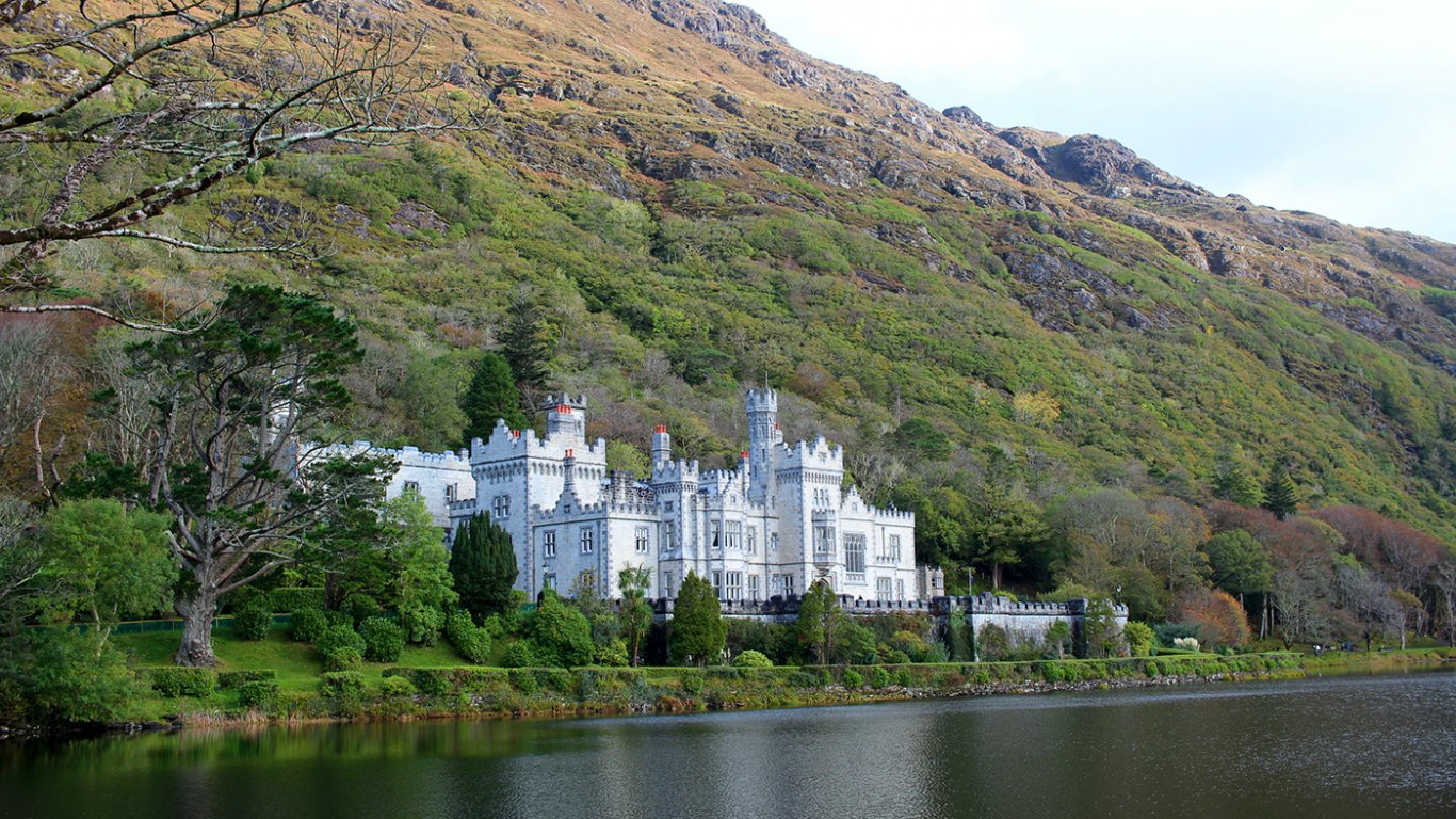 Kylemore Abbey surrounded by woodland and a lake 