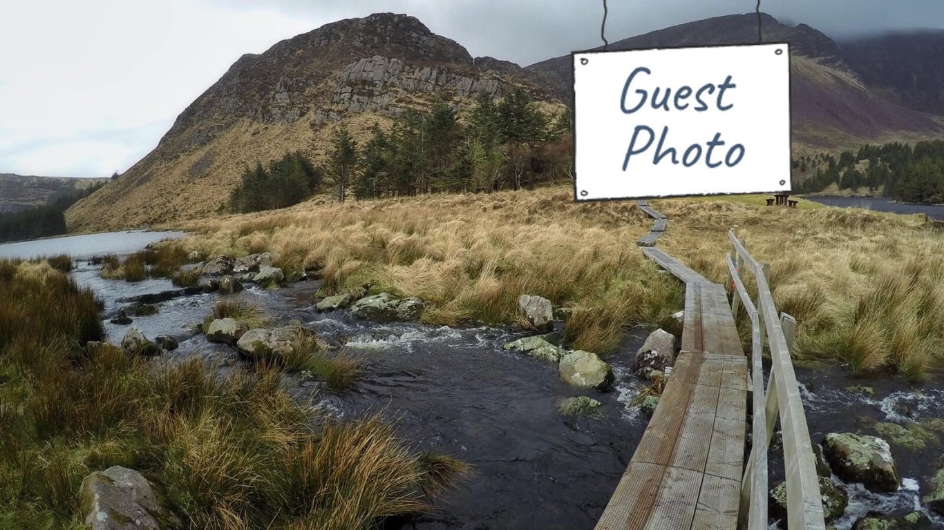 Scenic shot of mountain and bridge crossing river with Guest Photo graphic overlaid