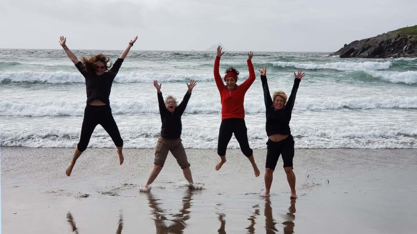 Four Vagabond Tours guests jump for joy on the beach in Ireland