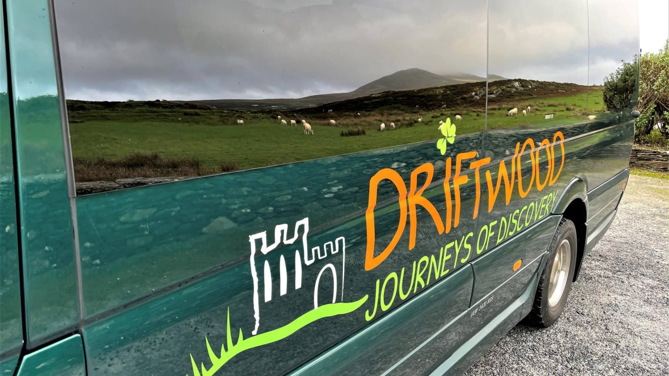 A Driftwood Tours vehicle with reflections of sheep and field