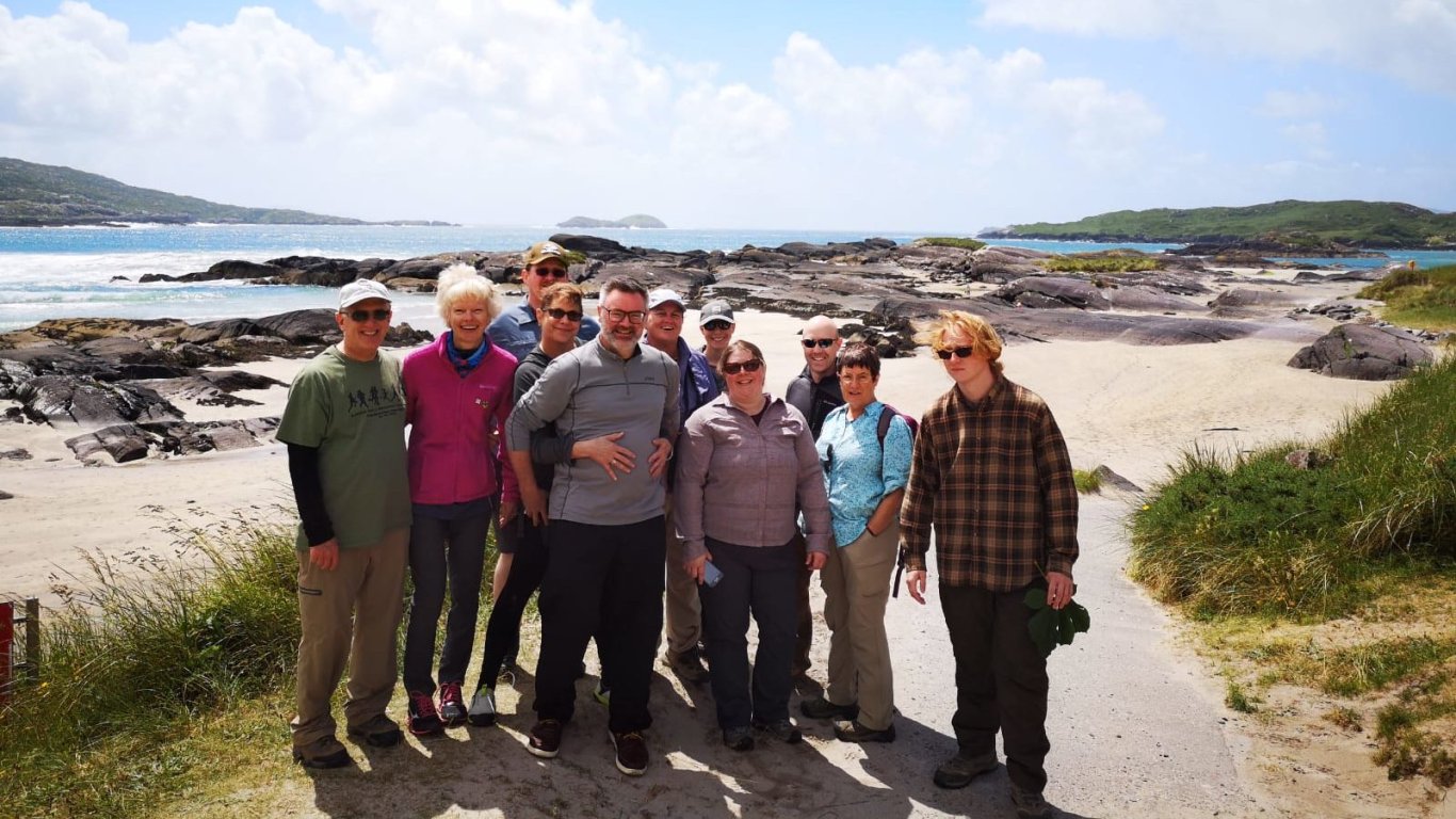 Vagabond tour group posing in the sunshine at Derrynane beach in Ireland