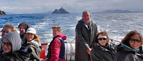 Tour group on boat in Ireland with Skellig Michael island in background