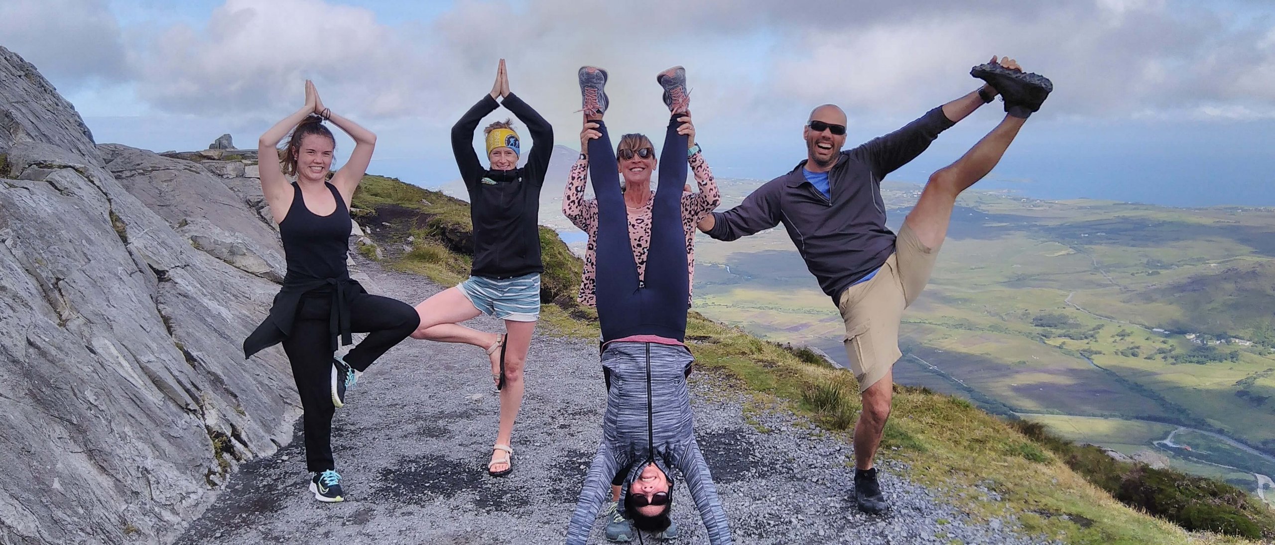 A tour group posing acrobatically on a mountain in Ireland