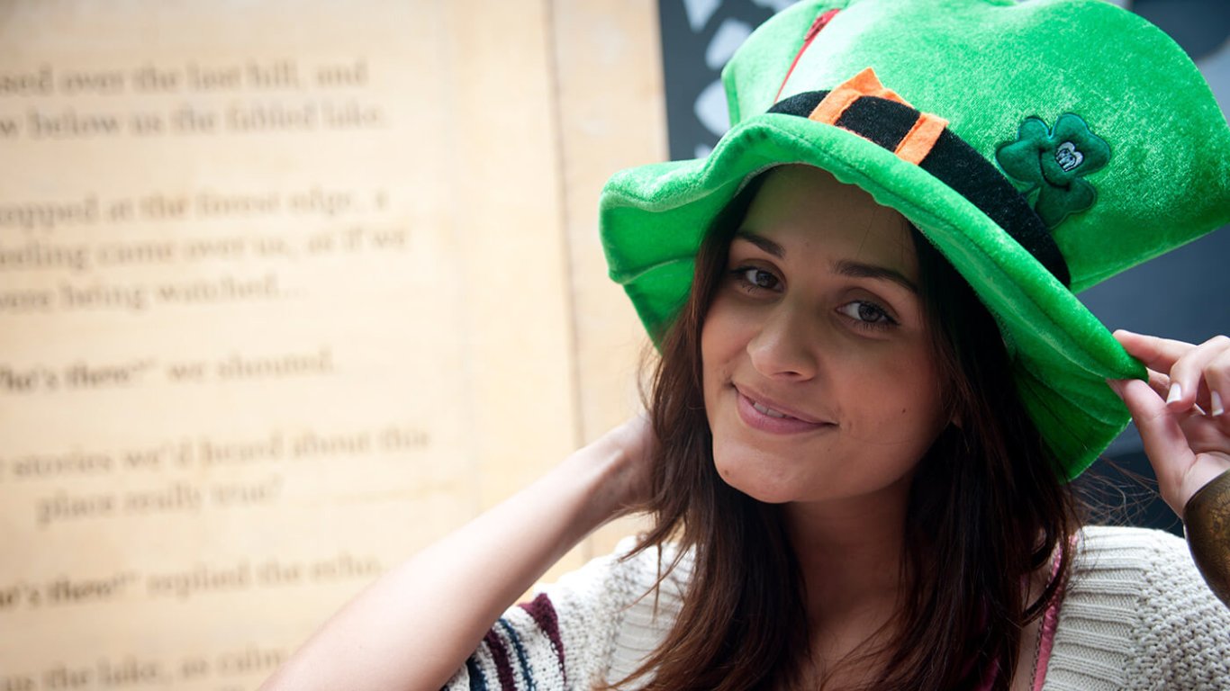 A girl wearing a green leprechaun top hat