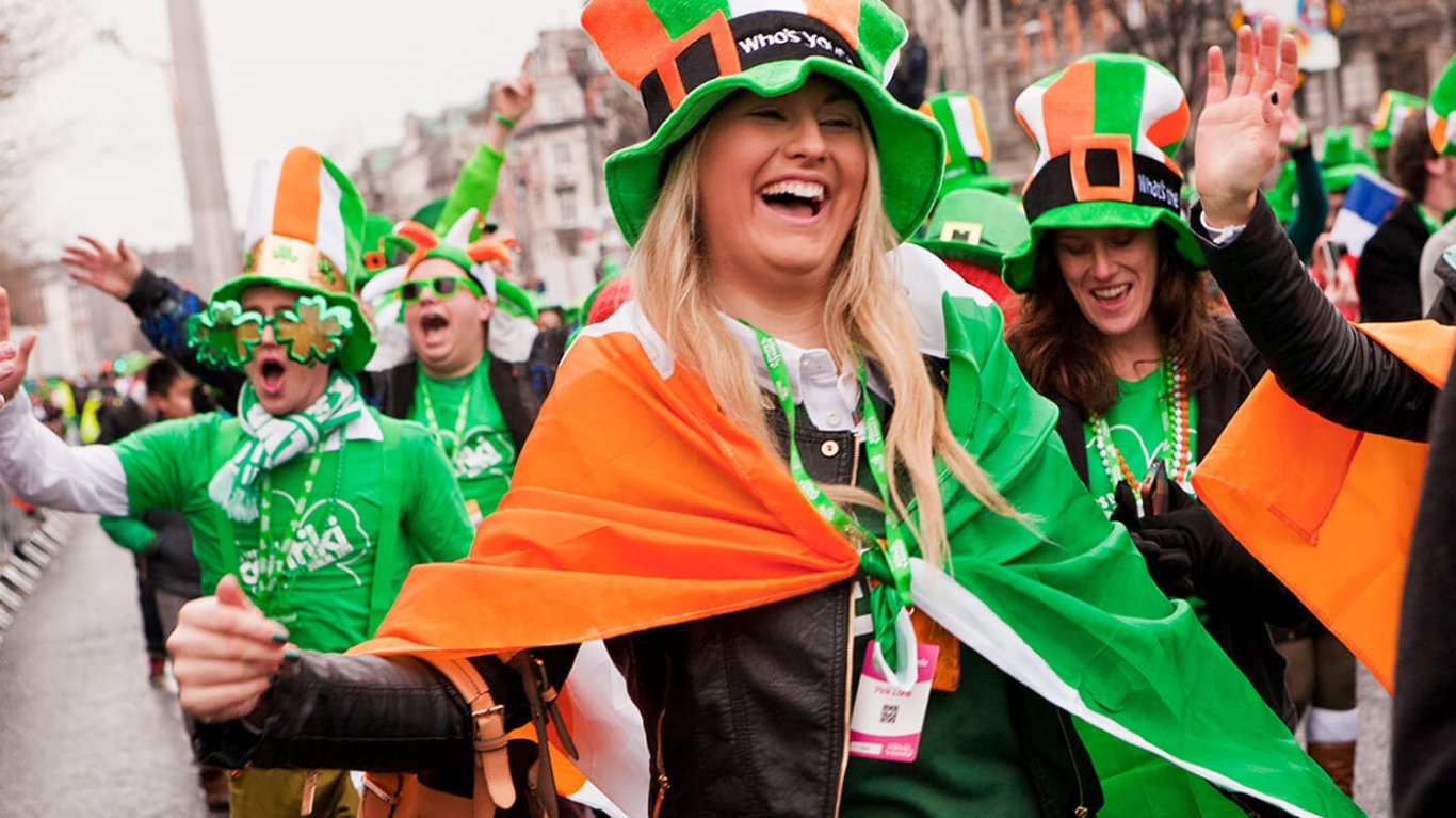 A group walking in the St Patrick's Day Parade with flags tied around them and Irish hats on