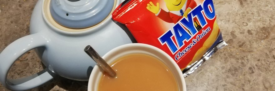 Cup of tea with teapot and pack of Tayto crisps in Ireland