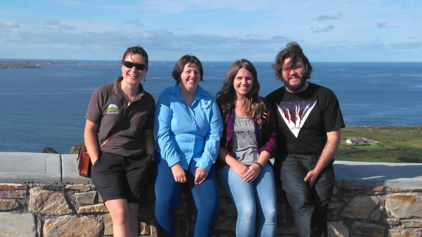 VagaGuide tour guide Bebhinn with three smiling guests in a scenic location in Ireland