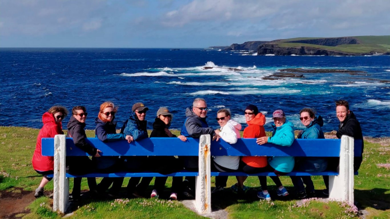 Tour group sitting on a bench at Kilkee Cliffs in Ireland
