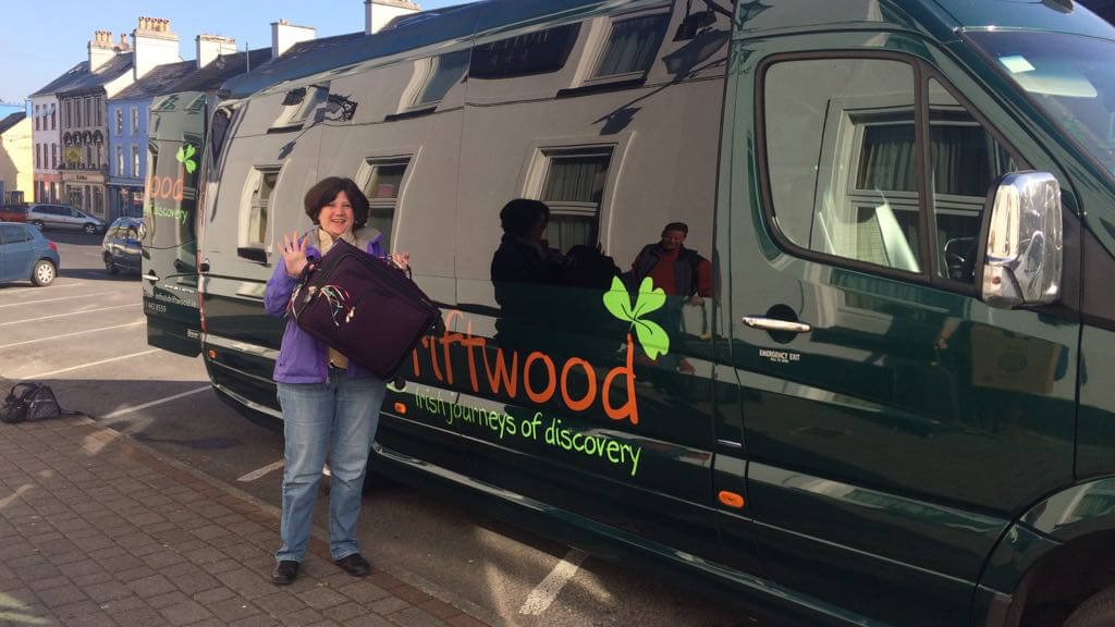A smiling Driftwood tour guest beside a Drifter tour vehicle in Ireland