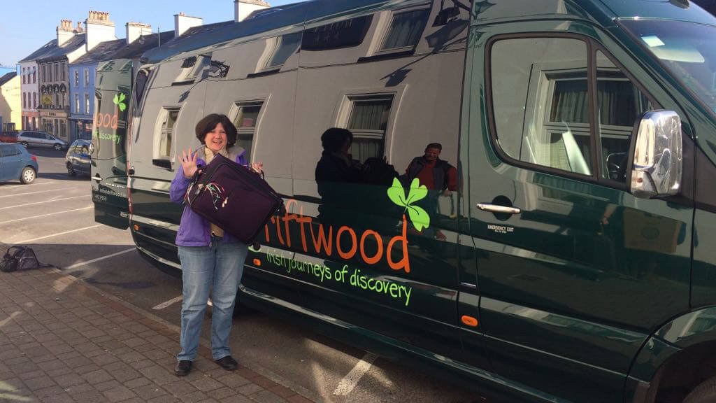 A Driftwood passenger holding a compact suitcase in front of a Drifter tour vehicle