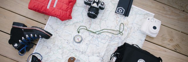 A selection of hiking materials including boots and a red fleece on a map