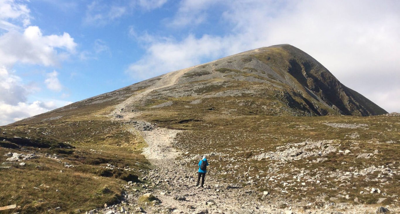 A guest standing at the bottom of Croagh Patrick mountain looking up to the top