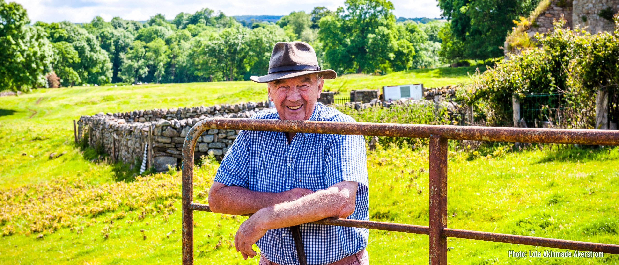 Smiling Irish male middle aged tour guide with a hat leaning on gate at Jerpoint in Kilkenny, Ireland