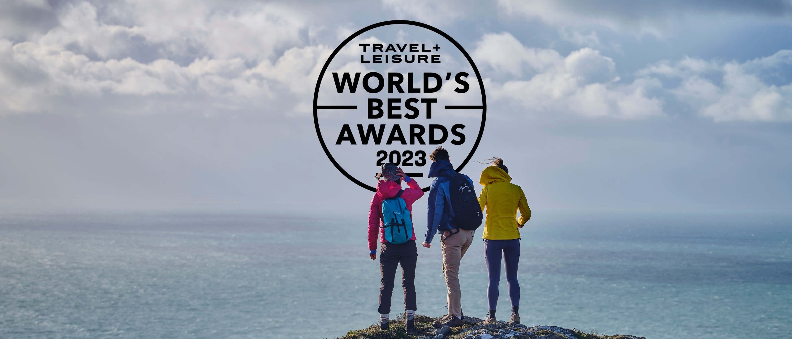 Three hikers with the Travel + Leisure World's Best Awards 2023 badge and a scenic seascape