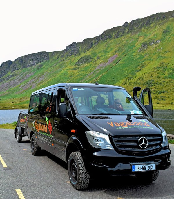 Black tour vehicle in a green valley in Ireland