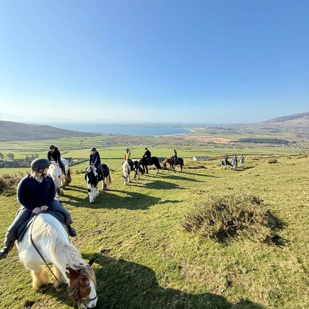 A group horse riding up a mountain on ventry beach
