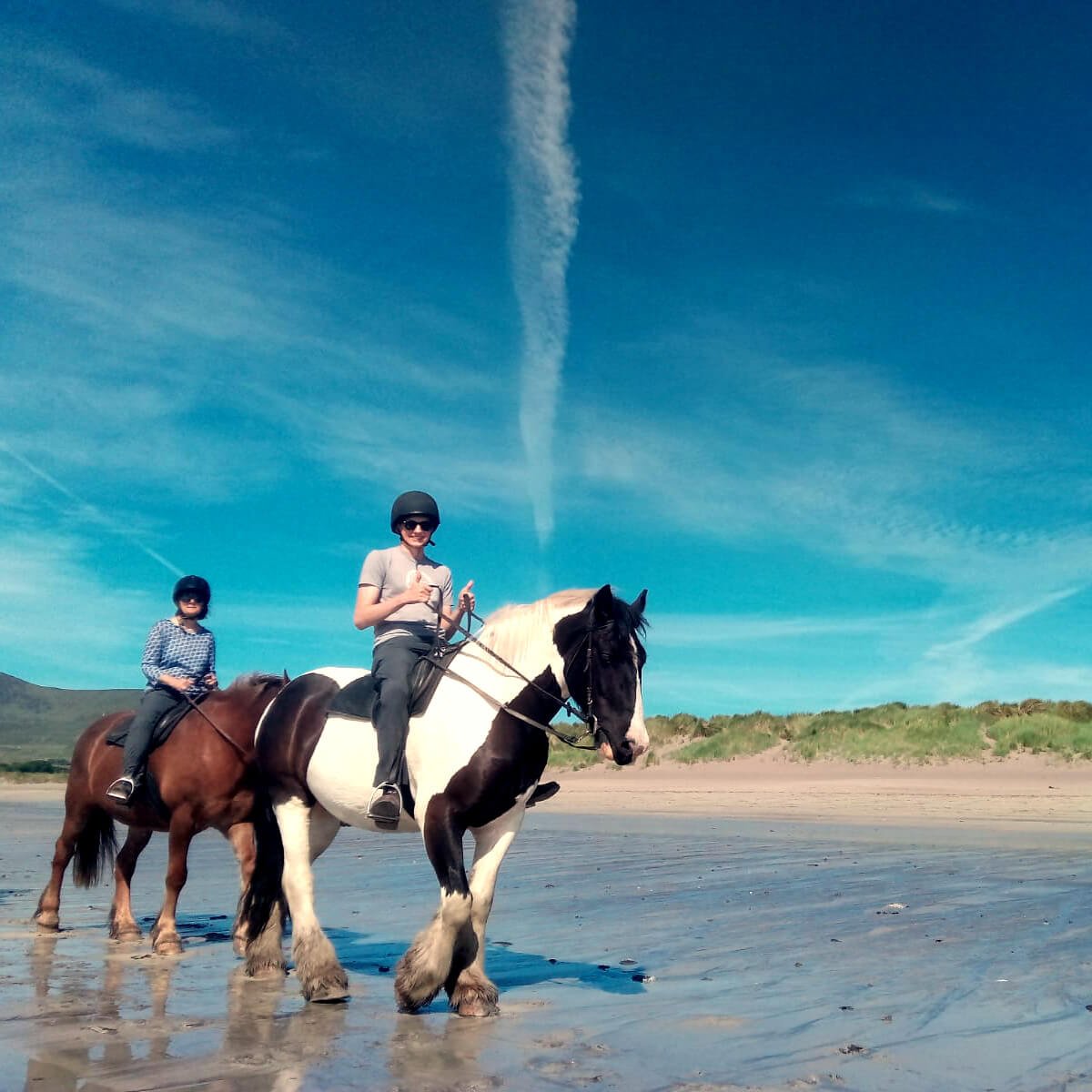 Two horseback riders on a beach in Ireland